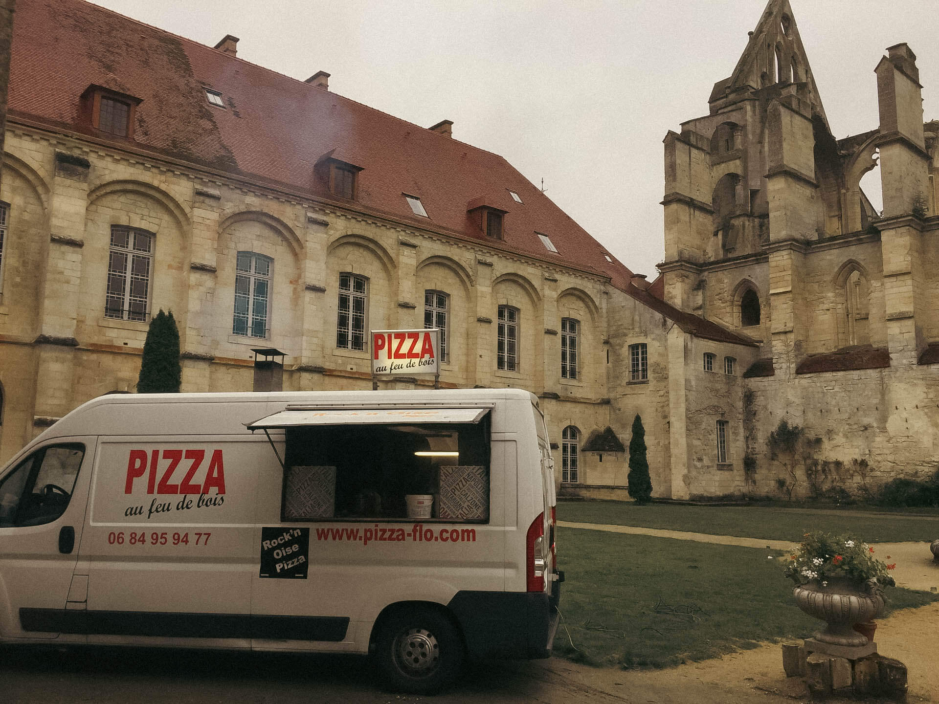 Photo d'un food truck de pizzas en prestation devant une abbaye